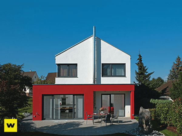 Modernes Einfamilienhaus mit roter Fassade und Garten unter blauem Himmel.